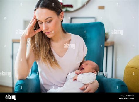 Stressed Mother Holding Crying Baby Suffering From Post Natal