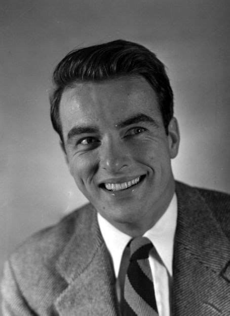 Black And White Photograph Of A Smiling Man In A Suit With A Striped Tie On