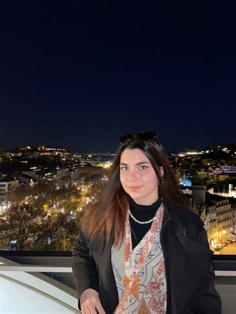 A Woman Standing On Top Of A Building At Night