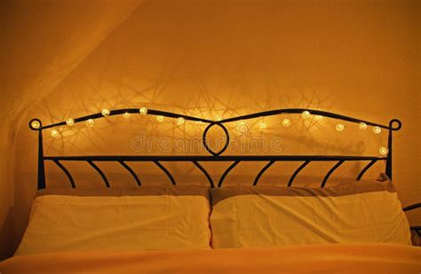 Romantic Cozy Bed With Garland Of Lights Around Headboard Stock Photo