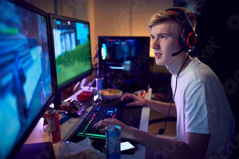 Teenage Boy Wearing Headset Gaming At Home Using Dual Computer Stock