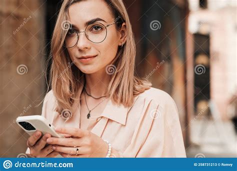 Close Up Portrait Of Confident Young Woman With Eyeglasses Texting On Smartphone While Walking