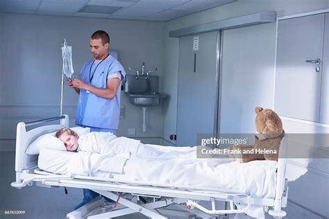Male Nurse Adjusting Intravenous Drip For Boy Patient In Hospital