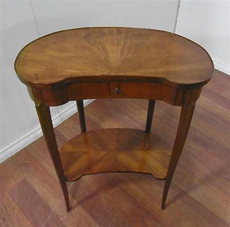 Medical instruments in a metal bowl. A French walnut kidney shaped one drawer side table with ...