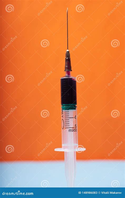 Medical Disposable Syringe With Blue Liquid On Orange Blue Background