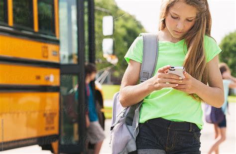 School Bus Girl Walking Home From Bus Checks Phone By Sean Locke