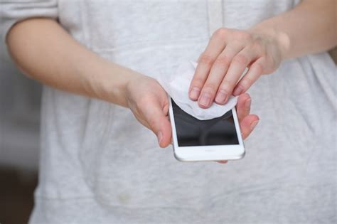 Person Cleaning Mobile Phone Screen With Disinfecting Wipes For Clean