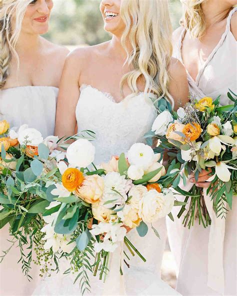 Three Bridesmaids In White Dresses Holding Bouquets With Orange And
