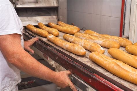 Baker Taking Out Fresh Baked Bread From The Industrial Oven Stock Photo