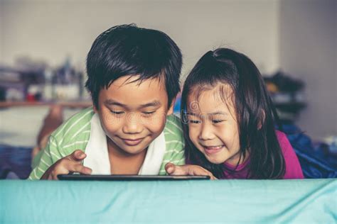 Asian Children Watching Video And Playing Game On Digital Tablet Stock