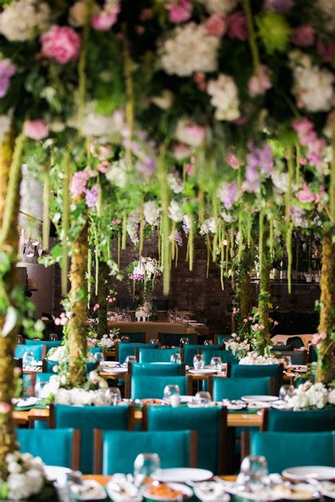 The Tables Are Set With Blue Chairs And Floral Arrangements Hanging From The Ceiling Over Them