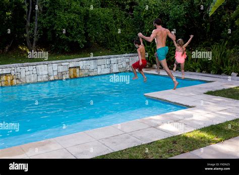 Father With Daughter And Son Jumping Into Swimming Pool Stock Photo Alamy