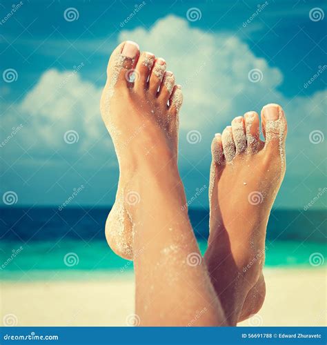 Tanned Feet Of Woman And White Bikini On Sand Royalty Free Stock Photo