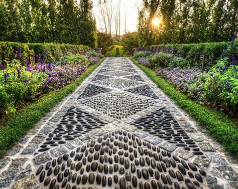 A Stone Pathway With Stepping Stones In The Middle And Purple Flowers