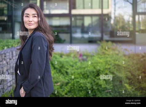 Asian confident business woman in suit smiling, looking up to the