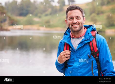 adult man on a camping holiday standing by a lake smiling to camera portrait lake district uk