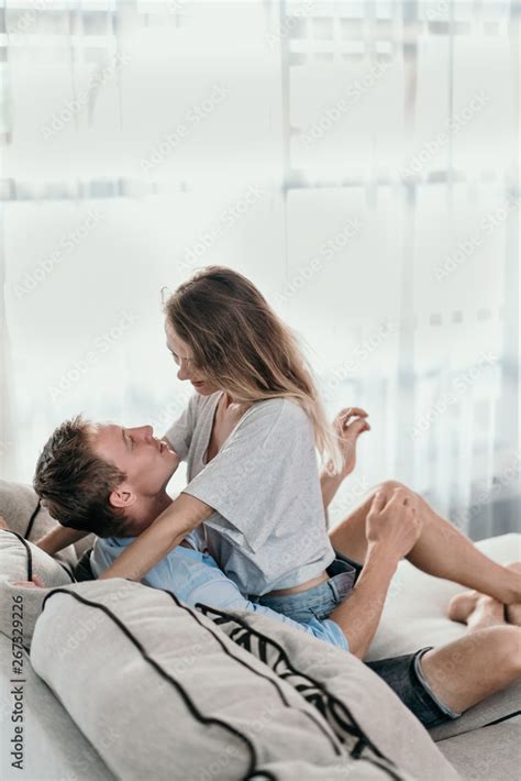 Beautiful Young Couple Embracing While Sitting Face To Face On A Couch