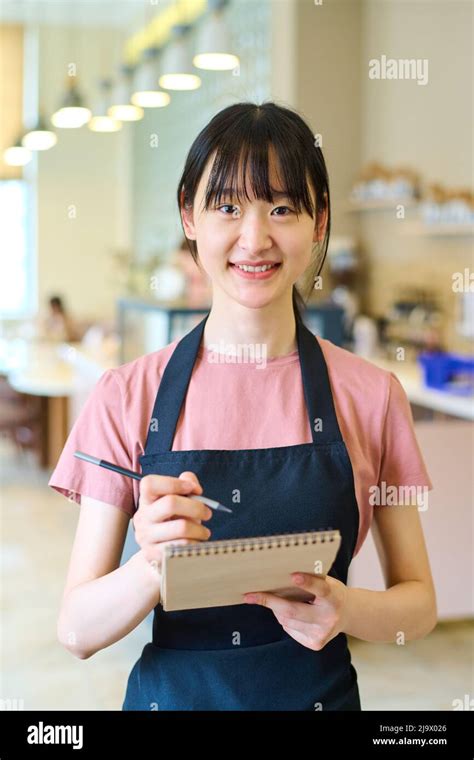 Portrait Of Asian Young Waitress In Apron Smiling At Camera While