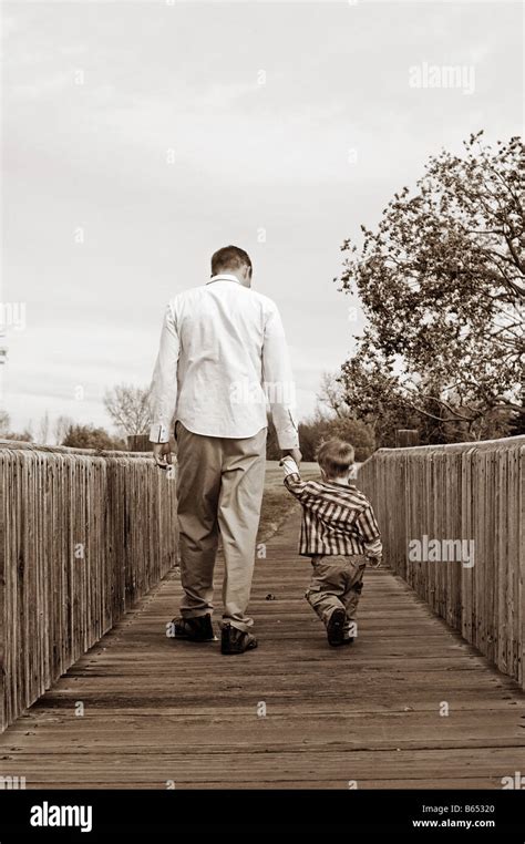 Father Holding His Young Sons Hand Crossing A Bridge Stock Photo Alamy