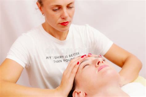 beautician massaging woman`s face attractive girl having facial treatment and massage the