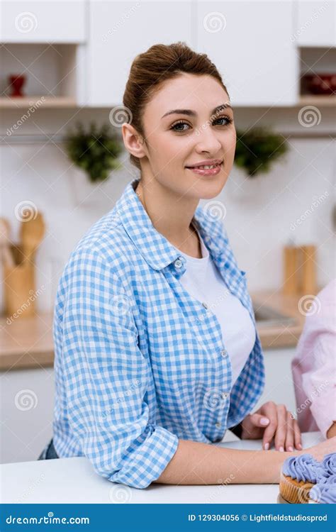 Attractive Young Woman Sitting At Kitchen And Looking Stock Photo