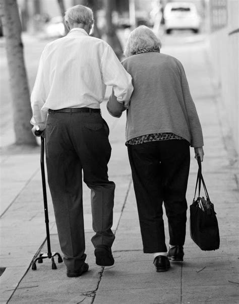 an older couple walking down the sidewalk holding hands