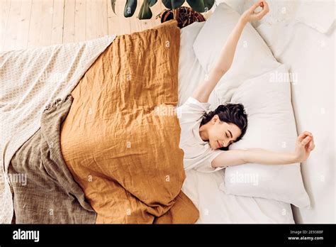 Lifestyle Portrait Of A Happy Young Girl Waking Up And Stretching In