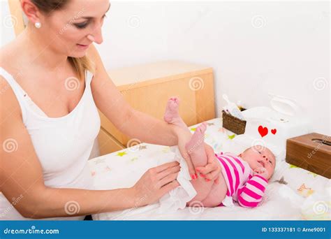 La Madre Limpia Las Nalgas Del Bebé Con El Tejido Mojado Imagen De