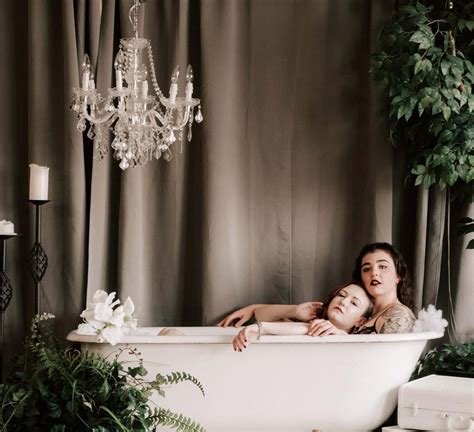 Two Women In Lingerie Pose For A Photoshoot In A Bathtub Surrounded By