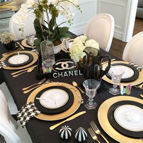 A Black And Gold Table Setting With White Flowers