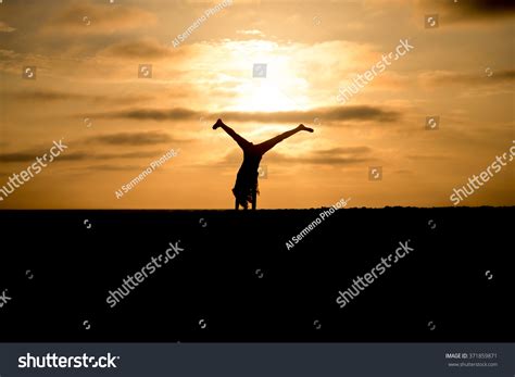 Silhouette Woman Doing Handstand On Beach Stock Photo