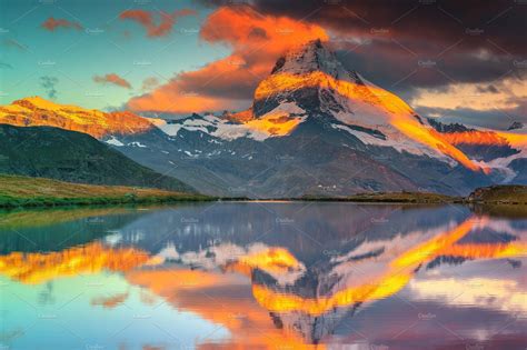 The Mountain Range Is Reflected In The Still Water At Sunset With