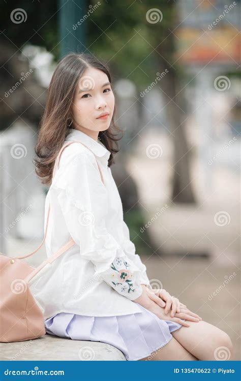 portrait of asian girl with white shirt and skirt sitting and looking in outdoor nature vintage