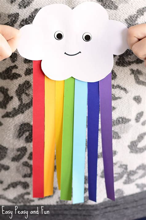 A Person Holding Up A Paper Cloud With Rainbows On It