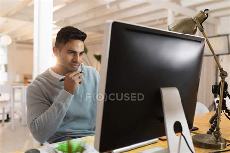 Front View Close Up Of A Young Mixed Race Man Sitting At A Desk And