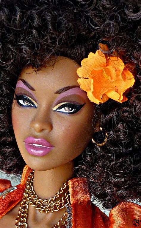 A Close Up Of A Doll With Curly Hair And An Orange Flower In Her Hair