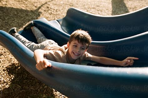 Boy Sliding Down Slide Backwards By Stocksy Contributor Maria Manco