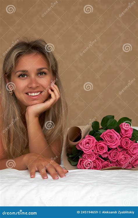 blonde tanned girl poses in a room close up with a bouquet of pink roses stock image image of