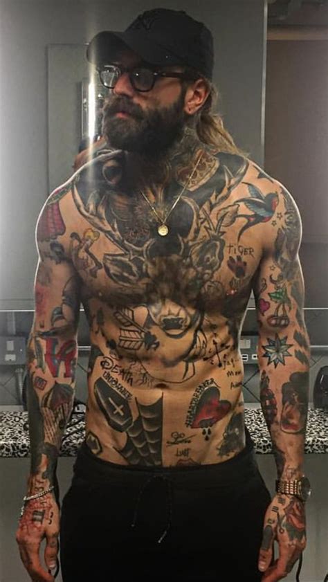 A Man With Lots Of Tattoos On His Chest And Arms Standing In Front Of A Mirror