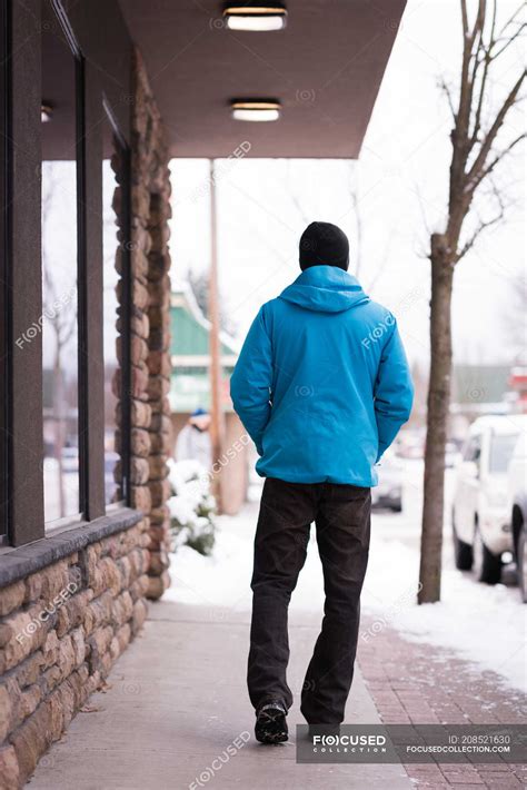 Man Walking With Hands In Pockets On Sidewalk During Winter — Travel