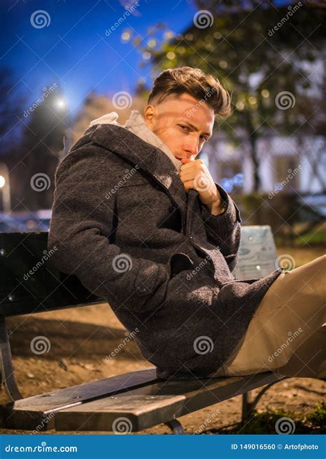 Handsome Trendy Young Man Sitting On Bench At Night Stock Photo