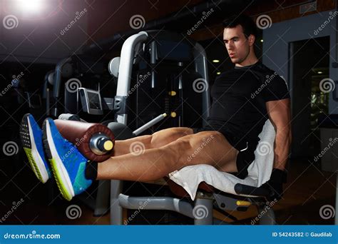 Young Bodybuilder Flexing Legs Muscles On Gym Machine Stock Photo