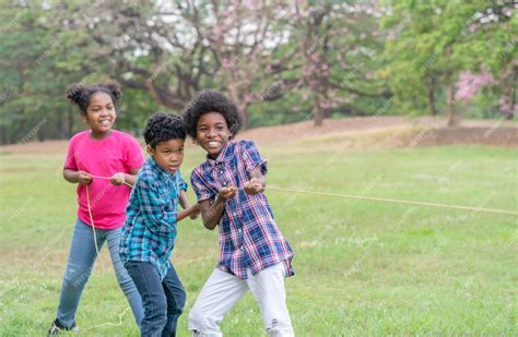 Счастливые афро американские дети играют в перетягивание каната в парке