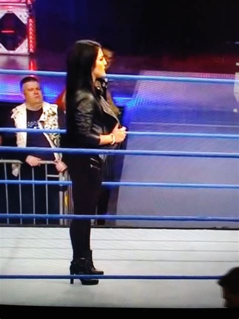 A Woman Standing On Top Of A Wrestling Ring Next To A Man In A Black Jacket