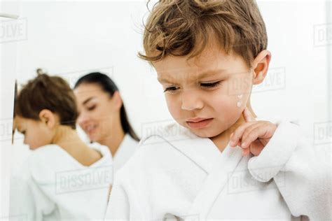 Confused Toddler Boy Touching Cheek With Face Cream Stock Photo