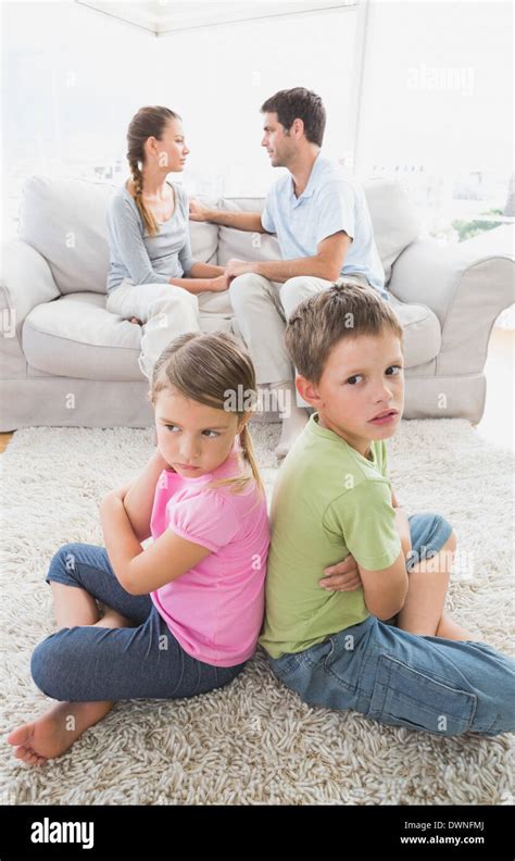 Pouting Siblings Sitting Back To Back While Parents Are Arguing Stock