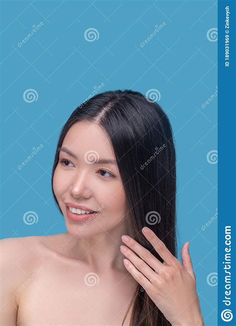 Beautiful And Smiling Long Haired Woman Touching Her Hair Stock Image