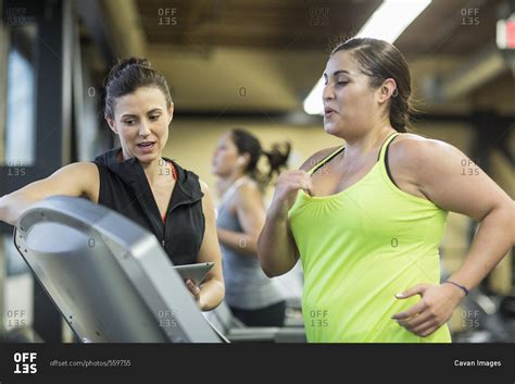 Trainer Instructing Woman Exercising On Treadmill In Gym Stock Photo