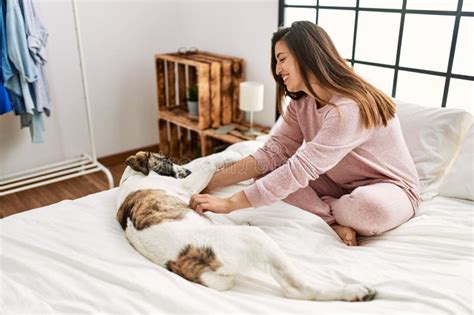 Young Woman Smiling Confident Playing With Dog Sitting On Bed At