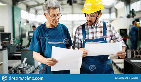 Factory Worker Discussing Data With Supervisor In Metal Factory Stock